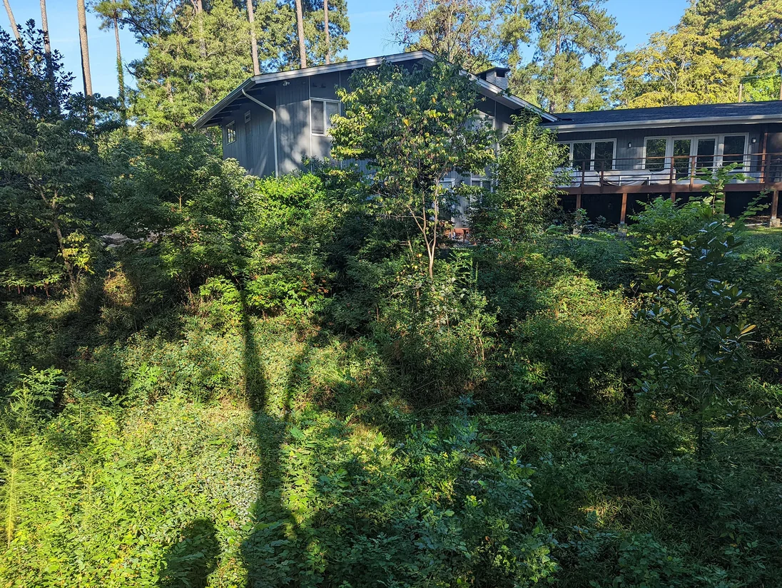 Steep eroded slope before boulder retaining wall installation
